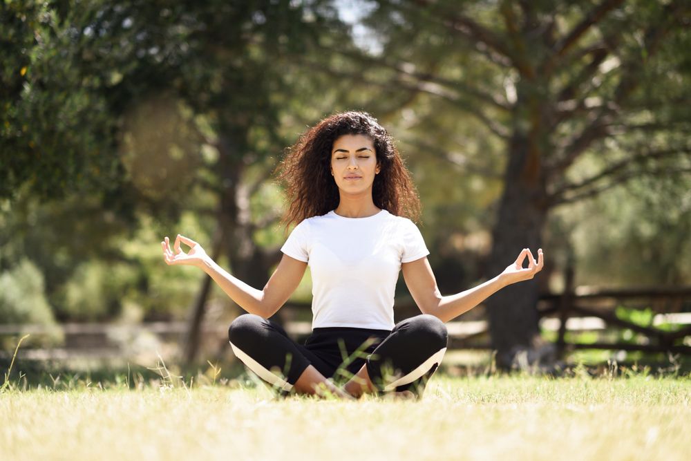 Arab woman doing yoga in field