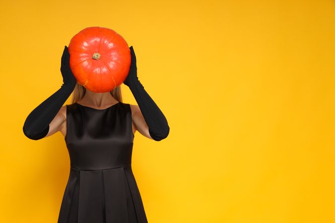 A woman in a Halloween outfit, with a pumpkin instead of a head
