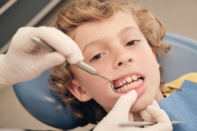 Faceless dentist checking teeth of boy