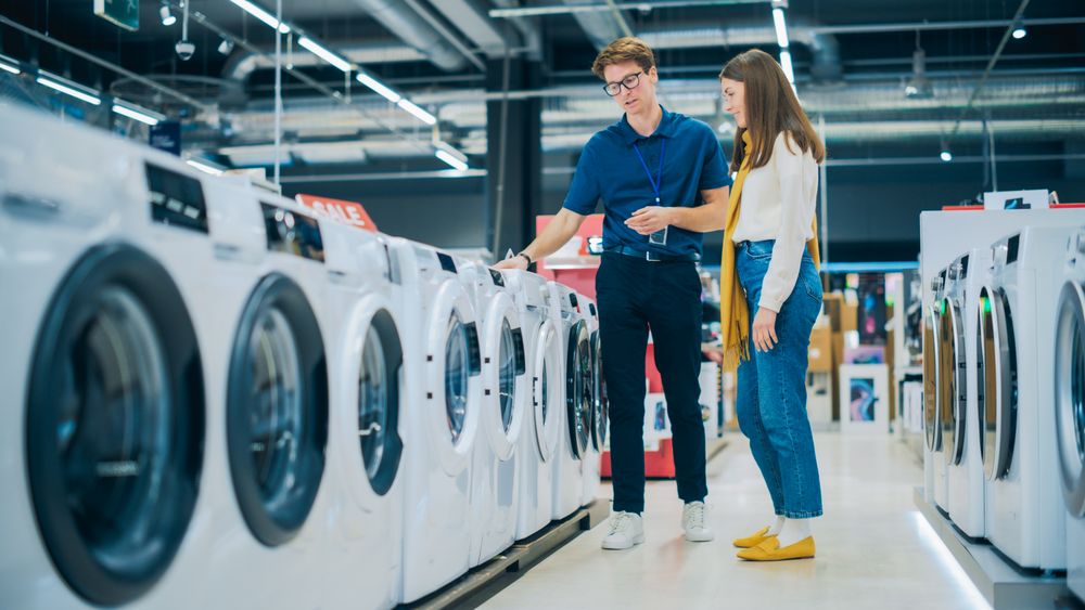 Portrait of a Female Customer Seeking Expert Advice from Retail Home Electronics Expert for Washing Machine Purchase.