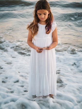 Smiling girl standing on seaside among waves