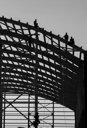 Grayscale photo of men working on building construction