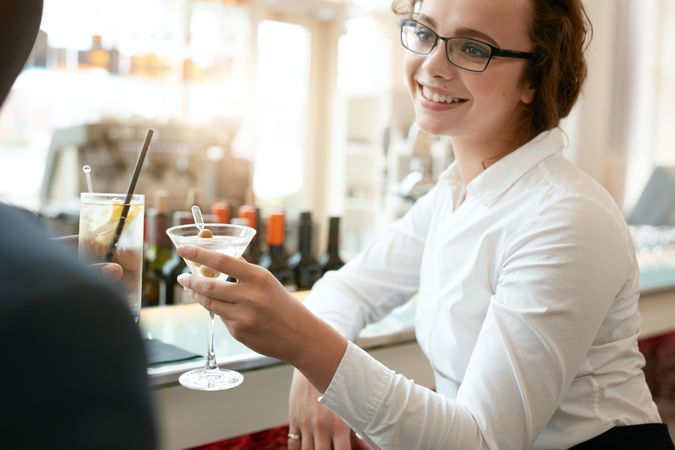 Young business woman toasting drinks with colleague at bar