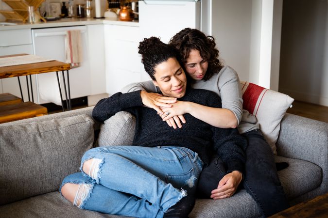 Loving female couple tenderly holding each other in living room