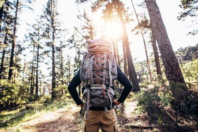 Man wearing a hiker backpack walking on forest trail