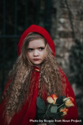 Young girl wearing red cape and holding flowers 0ydl7b