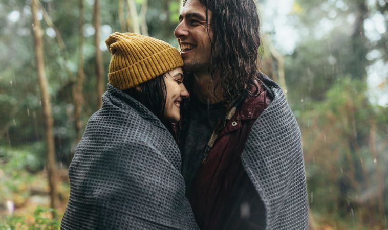 Cozy couple staying warm under a blanket on a winter day