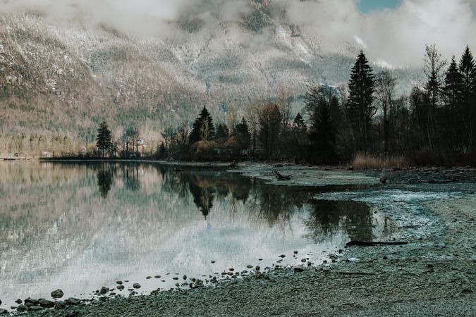 Empty shore with crystal lake reflecting sky and mountain