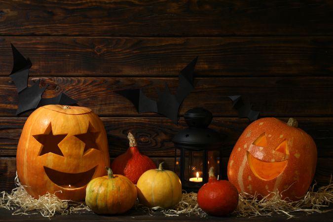 Halloween pumpkins and candles on dark wooden background, copy space