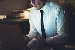 Cropped shot of man in shirt and tie working on his laptop