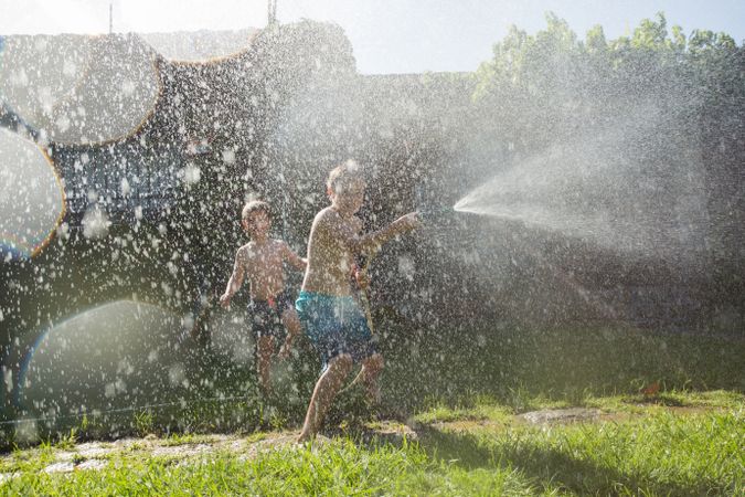 Little kids in swimwear having fun with splashing water