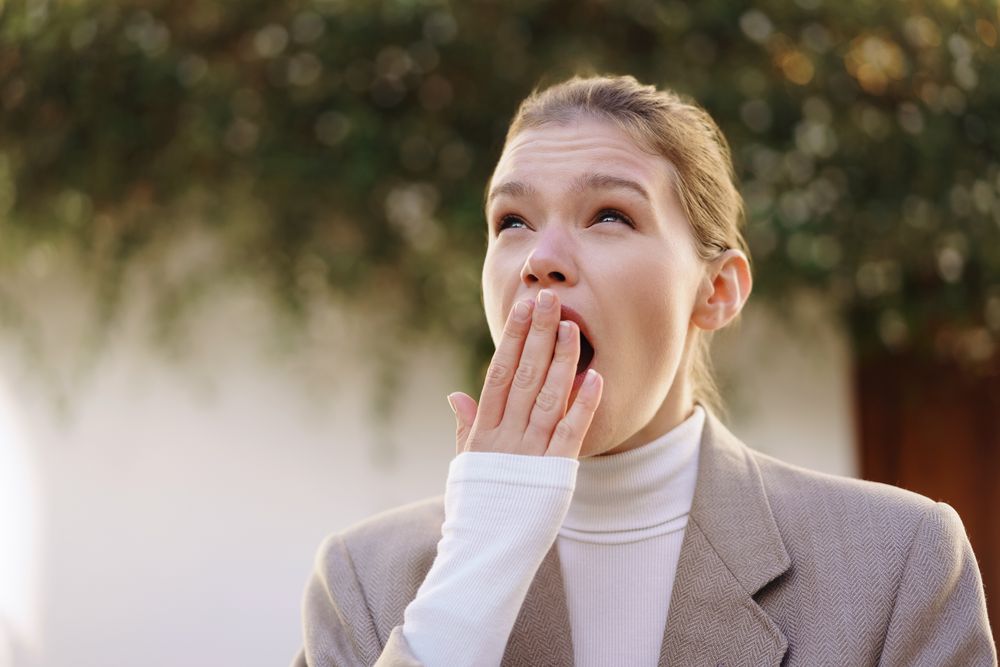 Stressed Businesswoman Yawning Outdoors  Capturing a Moment of Fatigue and Overwork