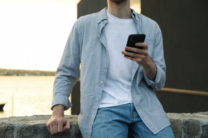 Young man uses a phone outdoor. Writing a message