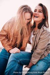 Two young women laughing and smiling with each other e4BvM4