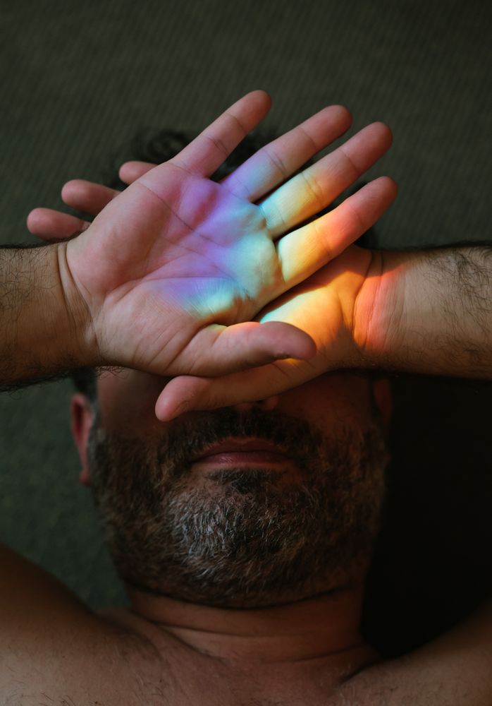 Bearded man covering eyes from rainbow glare