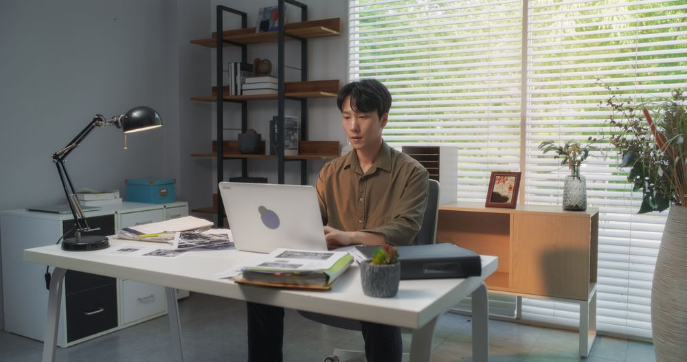 Efficient Asian Project Manager Working Diligently on a Laptop Computer in a Creative Agency Office