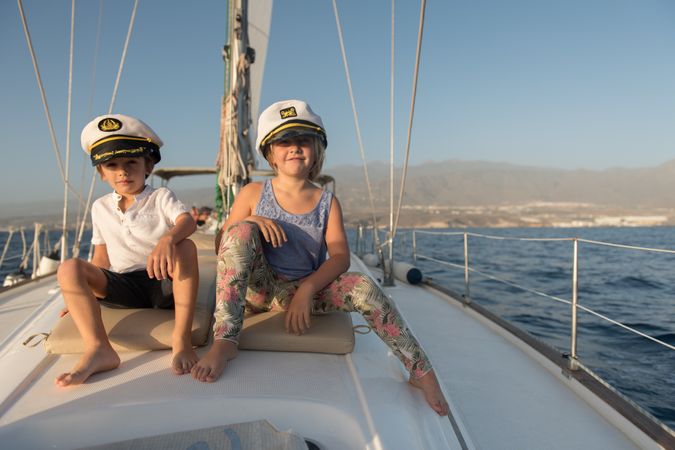 Smiling children sitting on deck of yacht in sea