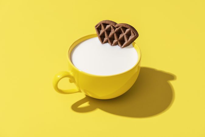 Cup of milk and a waffle isolated on a yellow background