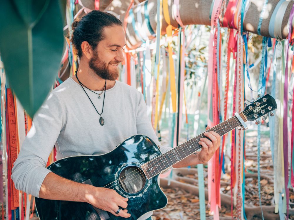Man playing guitar under decorated tree