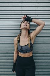 Sportswoman resting on a metal wall