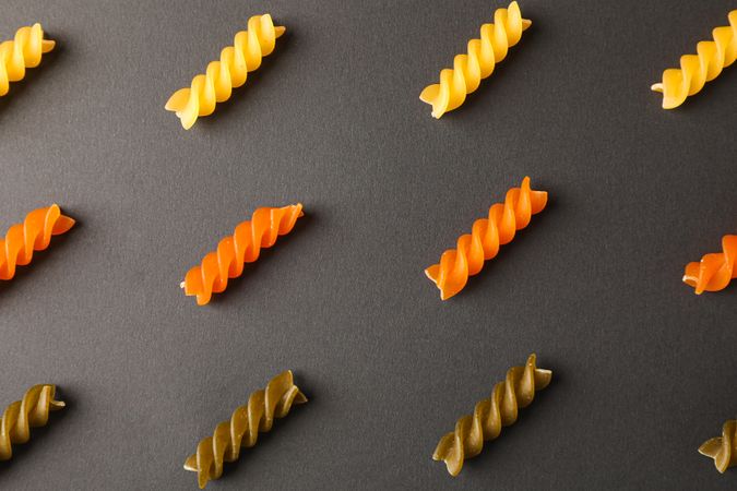 Flat lay composition with multicolored pasta on dark background, space for text and closeup
