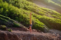 Young woman taking Handstand pose in nature