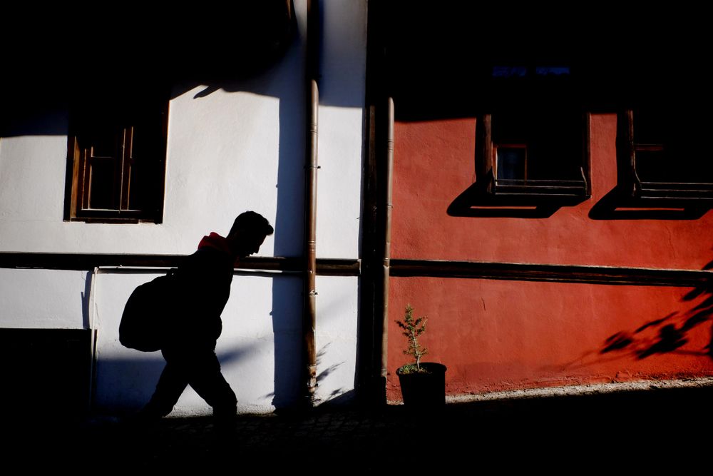 Man's shadow wearing backpack on sidewalk