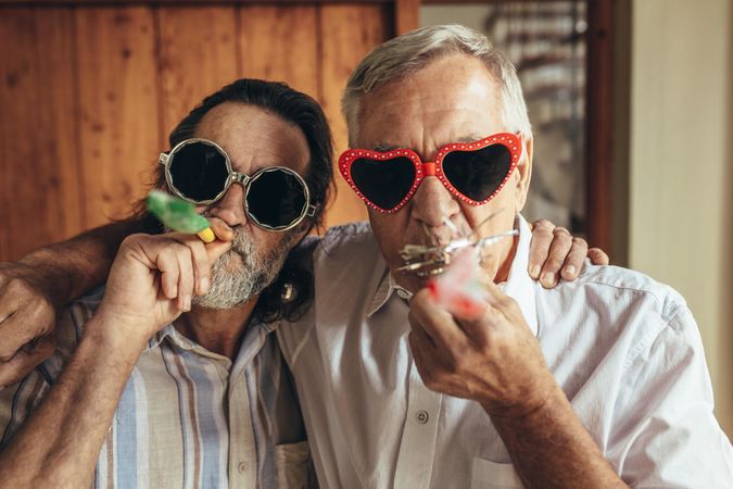 Two older friends with party blowers