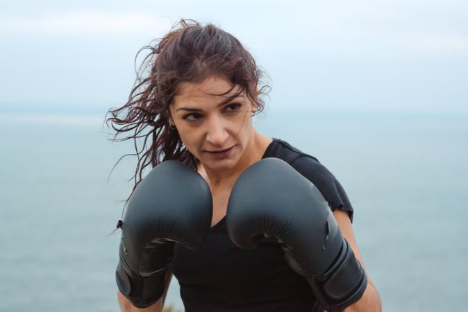 Woman Kickboxer training on cliff near sea