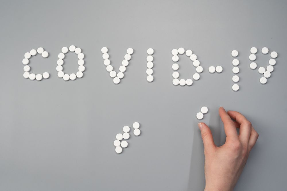 Cropped image of a person arranging pills to write "Covid-19"