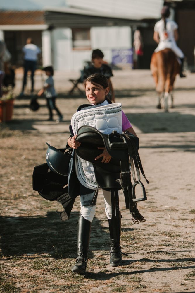 Girl carrying horse riding staff on ranch