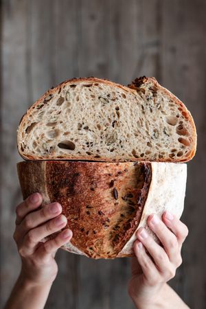 Crop person holding halved seeded bread