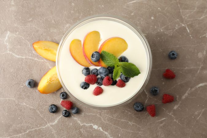 Bowl with sour cream yogurt and fruits on grey background