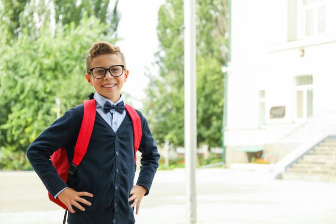 Boy with backpack against school building, space for text