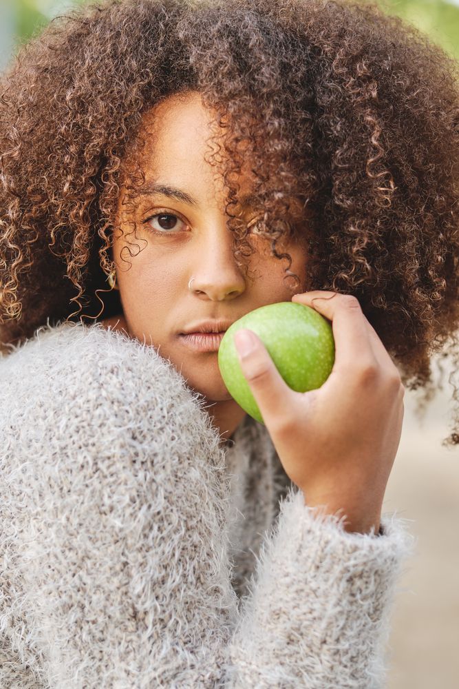 Curly haired Black woman with apple