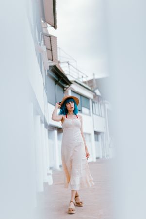Carefree woman in sundress walking along sunny street