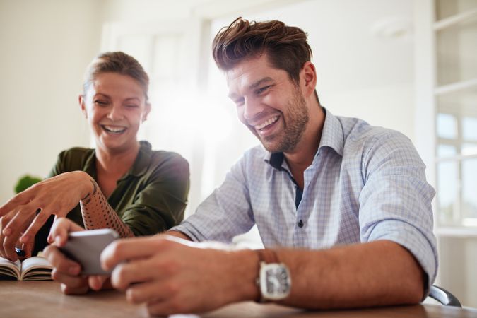 Man and woman smiling with mobile phone at home