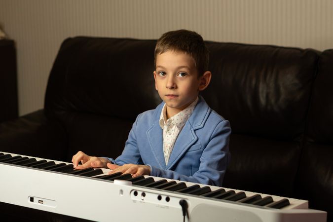 Young boy looking up while playing piano.