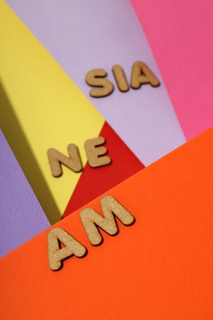 Scattered letters spelling “amnesia” on colorful paper background, vertical