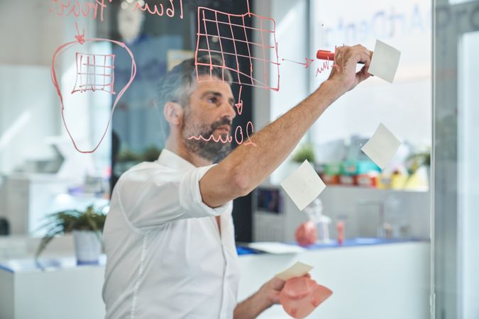 Concentrated worker with respirator writing on sticky notes