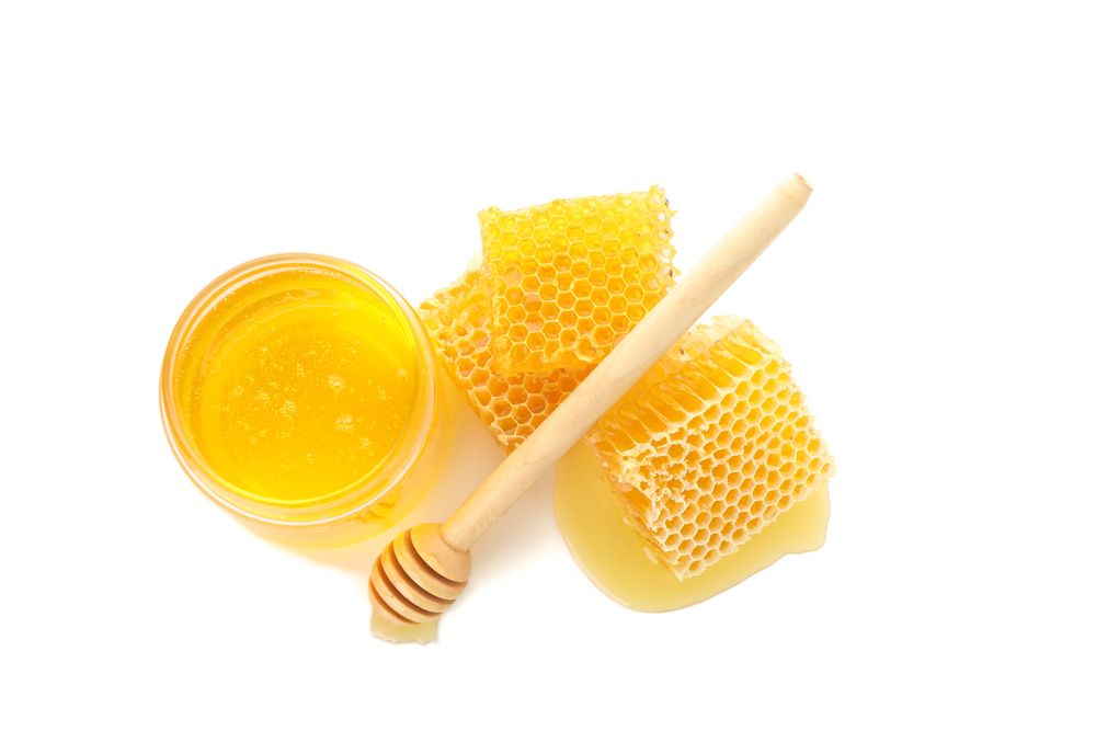 Pieces of honeycomb, glass jar and dipper isolated on plain background