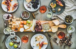 Charcuterie board with rose wine, hazelnuts, crackers, cheese, prosciutto, melon, wide composition
