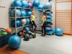 Sportswomen standing near equipment rack in gym