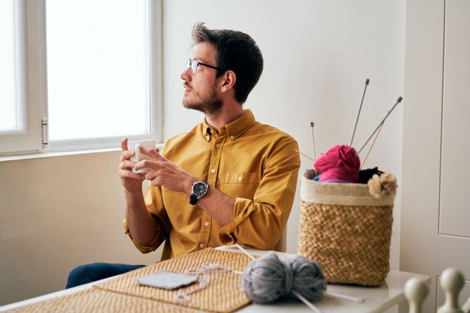Man drinking hot tea during knitting