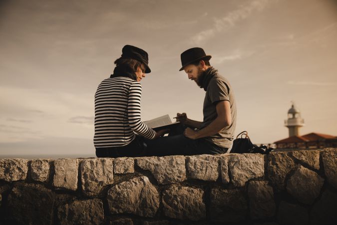 Man and woman on stones near lighthouse
