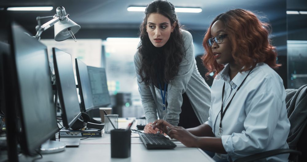 Two Diverse Colleagues Having a Conversation While Busy Working on a Team Project.