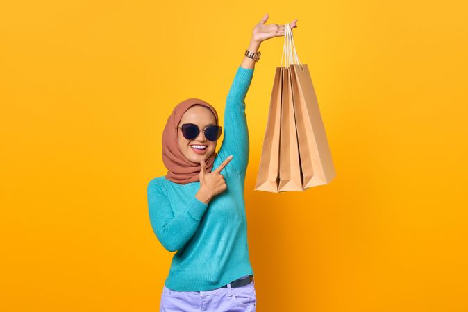 Fabulous Muslim woman holding shopping bags above her head