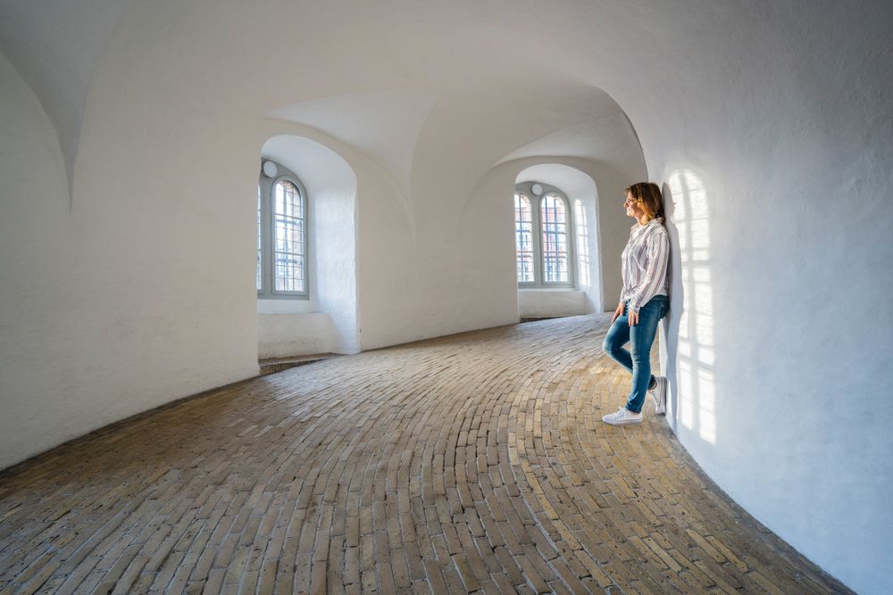 Casual woman leaning on wall in spacious gallery with windows