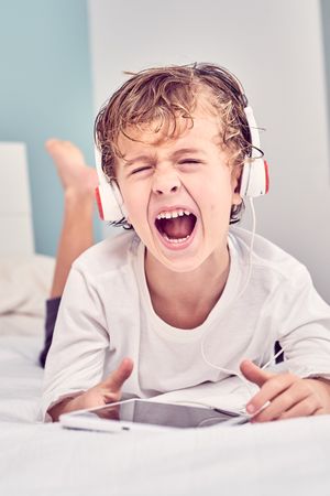 Boy screaming loud while listening to music from tablet