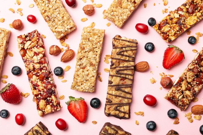 Tasty granola bars on pink background, top view